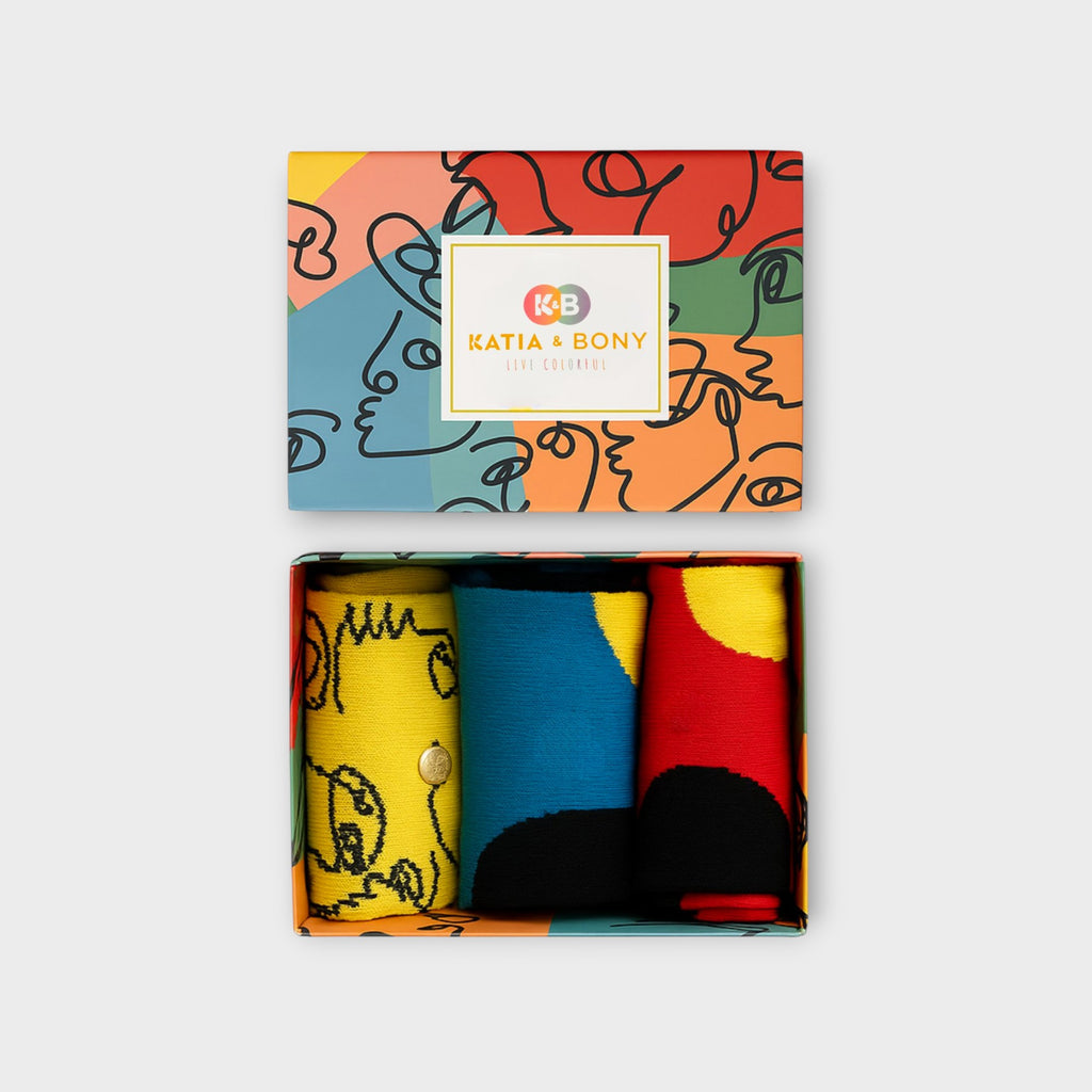 Katia und Bony Damen Socken Box geöffnet. Inhalt: Gelbe Socken mit schwarzen Linien-Gesichtern, blaue und rote Socken mit großen bunten Punkten.